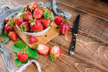 Tahta arka planda beyaz tabakta olgun tatlı çilekler. Boşluğu kopyala
