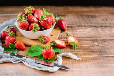 Tahta arka planda beyaz tabakta olgun tatlı çilekler. Boşluğu kopyala