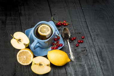 Siyah arka planda limonlu bir fincan çay.