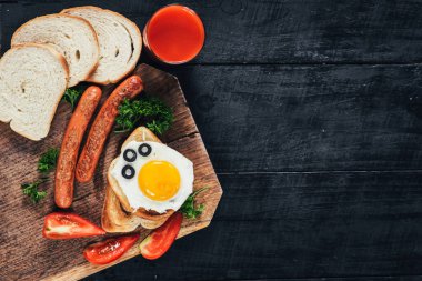 Kavrulmuş ekmek, çırpılmış yumurta ve siyah arka plandaki ahşap masada sosis. Boşluğu kopyala