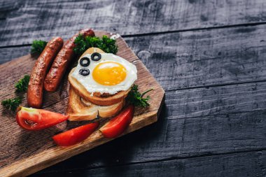 Kavrulmuş ekmek, çırpılmış yumurta ve siyah arka plandaki ahşap masada sosis. Boşluğu kopyala