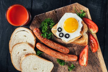 Kavrulmuş ekmek, çırpılmış yumurta ve siyah arka plandaki ahşap masada sosis. Boşluğu kopyala