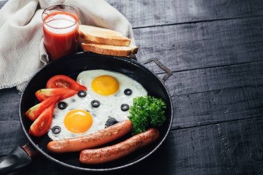 Tavada sosisli omlet ve siyah arka planda domates suyu. Boşluğu kopyala