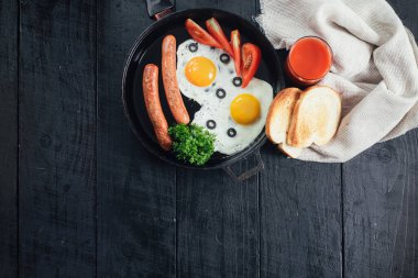 Tavada sosisli omlet ve siyah arka planda domates suyu. Boşluğu kopyala