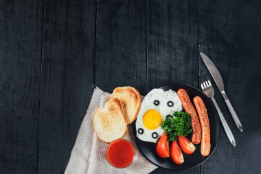 Tavada sosisli omlet ve siyah arka planda domates suyu. Boşluğu kopyala