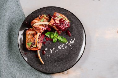 Ahşap arka planda kırmızı soslu ızgara pirzola.