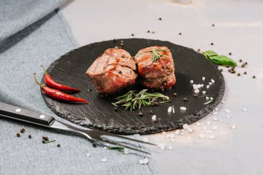 Ahşap arka planda baharatlı kızarmış et madalyonları.
