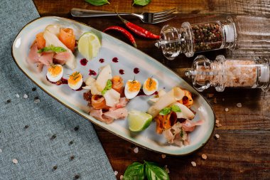 Ahşap zemin üzerinde kırmızı, beyaz balık, havyar ve sebze olan bir tabak.