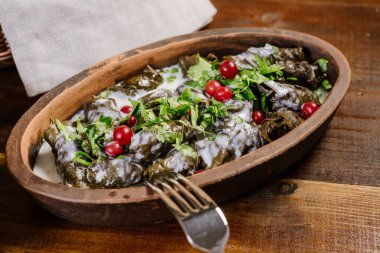 Doldurulmuş lahanalı tabak ve ahşap arka planda otlar.