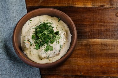 Dilimlenmiş et, sos ve ahşap arka planda otlar.