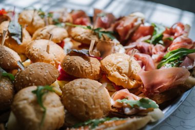 Büfede atıştırmalık bir sürü küçük hamburger var.