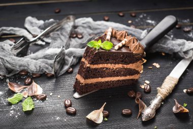 Siyah arka planda katmanları olan lezzetli bir parça çikolatalı pasta.