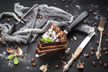 Siyah arka planda katmanları olan lezzetli bir parça çikolatalı pasta.