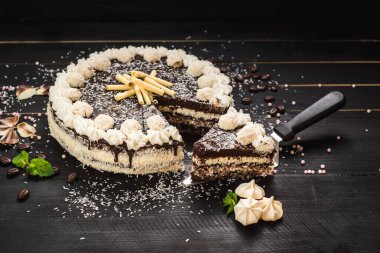 Çikolatalı beyaz pasta ve siyah ahşap arka planda krema.