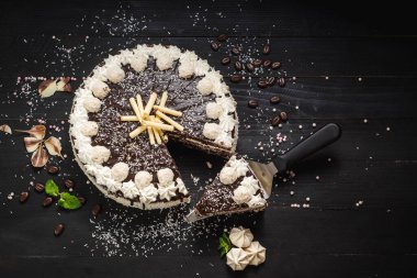 Çikolatalı beyaz pasta ve siyah ahşap arka planda krema.