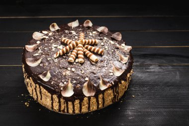 Siyah ahşap arka planda lezzetli kremalı tatlı çikolatalı pasta.