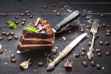 Siyah arka planda katmanları olan lezzetli bir parça çikolatalı pasta.