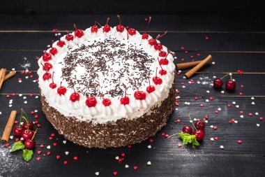 Siyah arka planda kremalı ve kirazlı tatlı beyaz pasta.