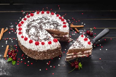 Siyah arka planda kremalı ve kirazlı tatlı beyaz pasta.