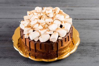 Tahta arka planda marşmelov olan çikolatalı pasta.