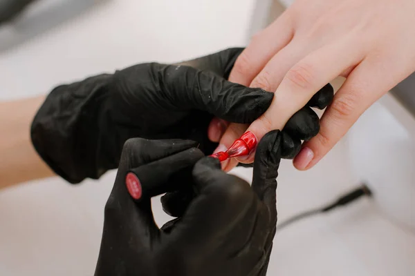 Beautician master applying color nail polish. Closeup