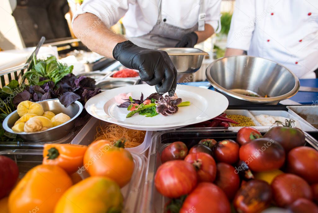 A cook preparing delicious dish with little octopuses at the open air restaurant