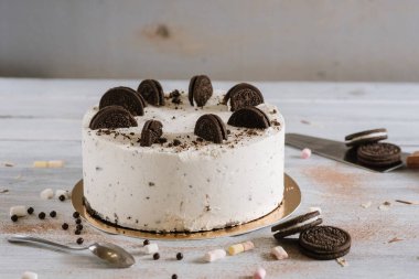 Beyaz arka planda çift kurabiyeyle süslenmiş tatlı beyaz pasta