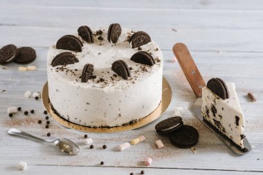 Beyaz arka planda çift kurabiyeyle süslenmiş tatlı beyaz pasta