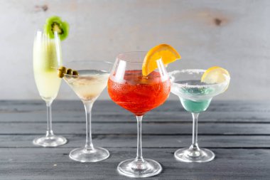 Ahşap arka planda gözlüklü renkli alkol kokteylleri.