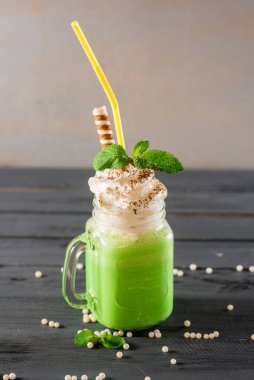 Ahşap zemin üzerinde cam içinde tatlı yeşil meyve suyu.