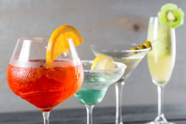 Ahşap arka planda gözlüklü renkli alkol kokteylleri.