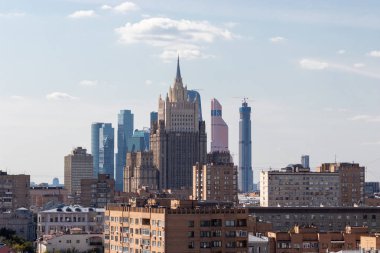Modern binalar eski binaların zemin üzerine. Çeşitli devirlerde bir fotoğraf. Mavi gökyüzü arka plan üzerinde büyük şehir. Yüksek bir binanın beyaz bulutlar spire dokunur. Moskova şehir.