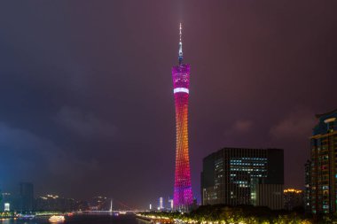 Kanton Tv Kulesi Guangzhou, geceleri, farklı renkleri kırmızı ve turuncu Parlatıcı. Nehir yüzen deniz araçları, şehir binaları, yeşil ağaçlar ile.
