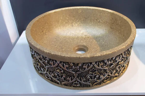 Round antique sink made of stone. Carved pattern on the sink in bronze. Beautiful stone sink in the bathroom.