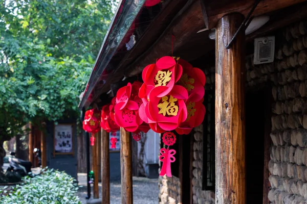 Festive Chinese decoration. Chinese red lanterns hang on the facade of a building on the street. Wooden stobla and roof.