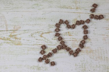 Kalp kahverengi gül yapılan bir okla deldi. Ahşap arka plan üzerinde Yukarıdaki fotoğraf. Aşk, Sevgililer Günü Bayramı. Kartpostal kopya alanı ile.