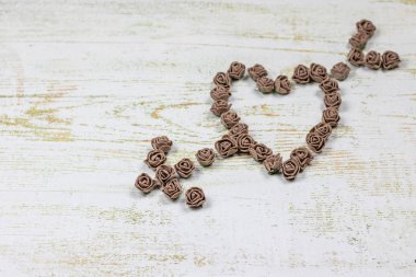 Kalp kahverengi gül yapılan bir okla deldi. Ahşap arka plan üzerinde bokeh fotoğraf. Aşk, Sevgililer Günü Bayramı. Kartpostal kopya alanı ile.