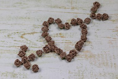 Kalp kahverengi gül yapılan bir okla deldi. Ahşap arka plan üzerinde bokeh fotoğraf. Aşk, Sevgililer Günü Bayramı. Kartpostal kopya alanı ile.