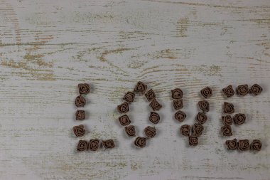 Ahşap arka plan, üstten görünüm üzerinde kahverengi gül koyu kahverengi aşk mektupları. Ahşap arka plan üzerinde metin aşk. Tatil sevgili için tebrikler.