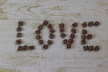 Ahşap arka plan, üstten görünüm üzerinde kahverengi gül koyu kahverengi aşk mektupları. Metin aşk merkezinde ahşap arka plan üzerinde. Tatil sevgili için tebrikler.