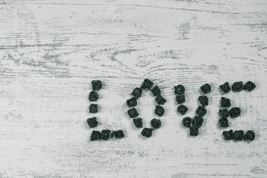 Ahşap arka plan, üstten görünüm üzerinde kahverengi gül karanlık aşk mektupları. Kağıt ahşap arka plan üzerinde kırmızı küçük kalpler. Tatil sevgili için tebrikler.