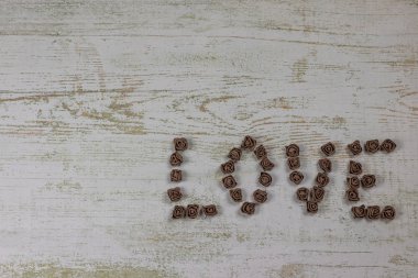 Ahşap arka plan, üstten görünüm üzerinde kahverengi gül koyu kahverengi aşk mektupları. Ahşap arka plan üzerinde metin aşk. Tatil sevgili için tebrikler.