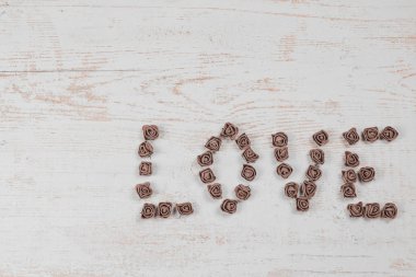 Ahşap arka plan, üstten görünüm üzerinde kahverengi gül koyu kahverengi aşk mektupları. Ahşap arka plan üzerinde metin aşk. Tatil sevgili için tebrikler.