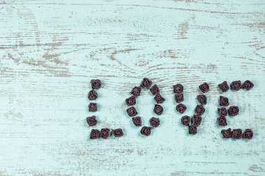 Ahşap arka plan, üstten görünüm üzerinde kahverengi gül koyu kahverengi aşk mektupları. Ahşap arka plan üzerinde metin aşk. Tatil sevgili için tebrikler.