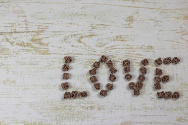 Ahşap arka plan, üstten görünüm üzerinde kahverengi gül koyu kahverengi aşk mektupları. Ahşap arka plan üzerinde metin aşk. Tatil sevgili için tebrikler.