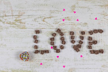 Aşk mektupları kahverengi ahşap arka plan, üstten görünüm güllerinin üzerinden. Kağıt ahşap arka plan üzerinde kırmızı küçük kalpler. Tatil sevgili için bir hediye.