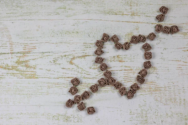 Kalp kahverengi gül yapılan bir okla deldi. Ahşap arka plan üzerinde Yukarıdaki fotoğraf. Aşk, Sevgililer Günü Bayramı. Kartpostal kopya alanı ile.