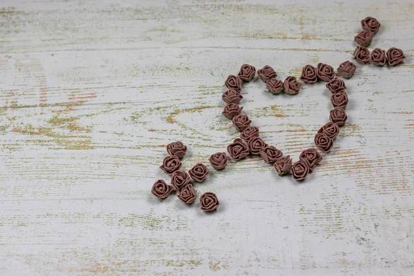 Kalp kahverengi gül yapılan bir okla deldi. Ahşap arka plan üzerinde bokeh fotoğraf. Aşk, Sevgililer Günü Bayramı. Kartpostal kopya alanı ile.