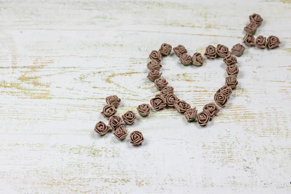 Kalp kahverengi gül yapılan bir okla deldi. Ahşap arka plan üzerinde bokeh fotoğraf. Aşk, Sevgililer Günü Bayramı. Kartpostal kopya alanı ile.