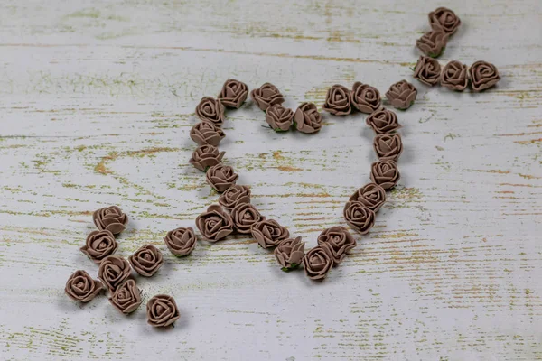 Kalp kahverengi gül yapılan bir okla deldi. Ahşap arka plan üzerinde bokeh fotoğraf. Aşk, Sevgililer Günü Bayramı. Kartpostal kopya alanı ile.